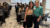 Courtney and Jade at Trendigital Rapid City, standing near a table with holographic stickers, with seated attendees and a projector screen in the background.