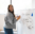 Smiling woman holding a marker beside a whiteboard labeled "brainstorm" with notes on website themes, process efficiencies, and client delight.