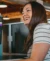 A woman smiling at her desk with Photoshop open.