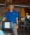 An employee in a blue Click Rain polo chats with and stands next to a man sitting at his desk working.