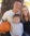 Family photo of female employee, fiance, and little boy during the falls. They are in front of a large tree and her fiance is holding a pumpkin.