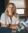 Female employee with a soft smile sitting at a desk with her arms crossed