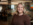 Renae smiling. She has short, wavy blonde hair and is wearing a brown button-up sweater.